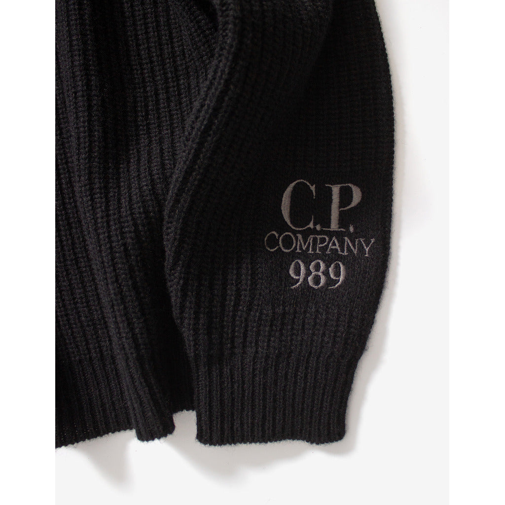 Close-up of the embroidered CP Company logo on the sleeve of the black wool sweater.