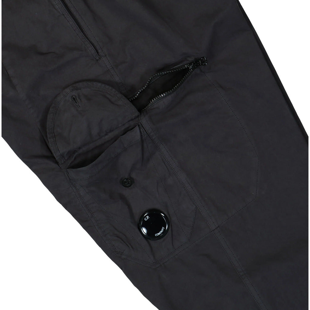 Close-up of the signature CP Company lens detail on the cargo pocket of the black Microreps pants.
