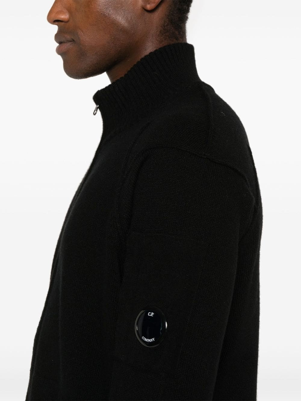 Close-up of the signature CP Company lens detail on the sleeve of the black labswool jumper.
