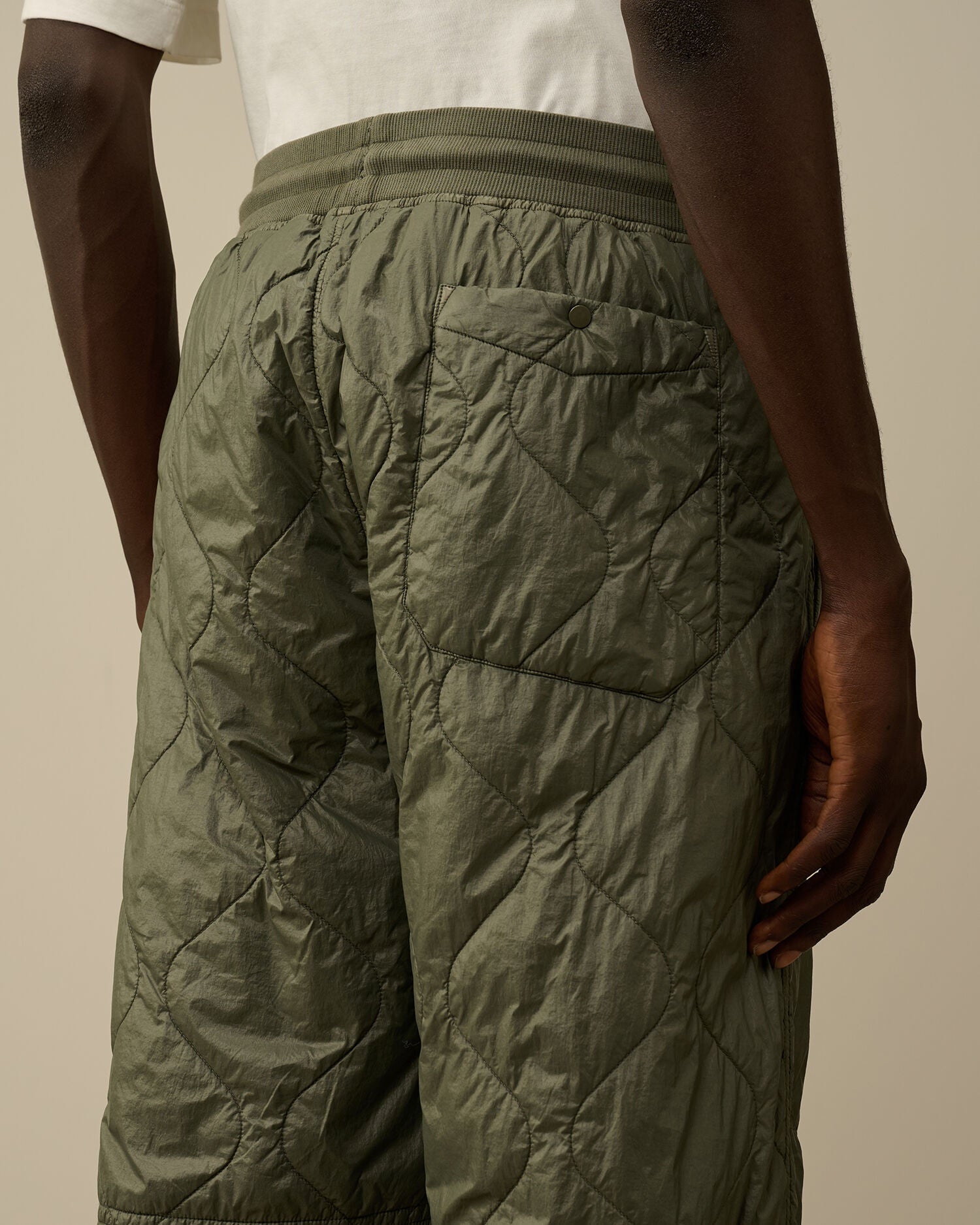 Back pocket close detail with button on the CP Company camo green quilted straight trousers