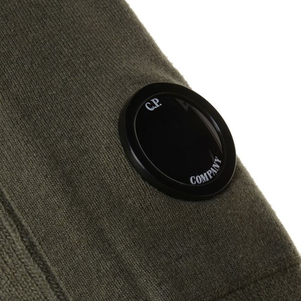 Close-up of the iconic CP Company goggle on the side zip pocket of the green wool blend sweater