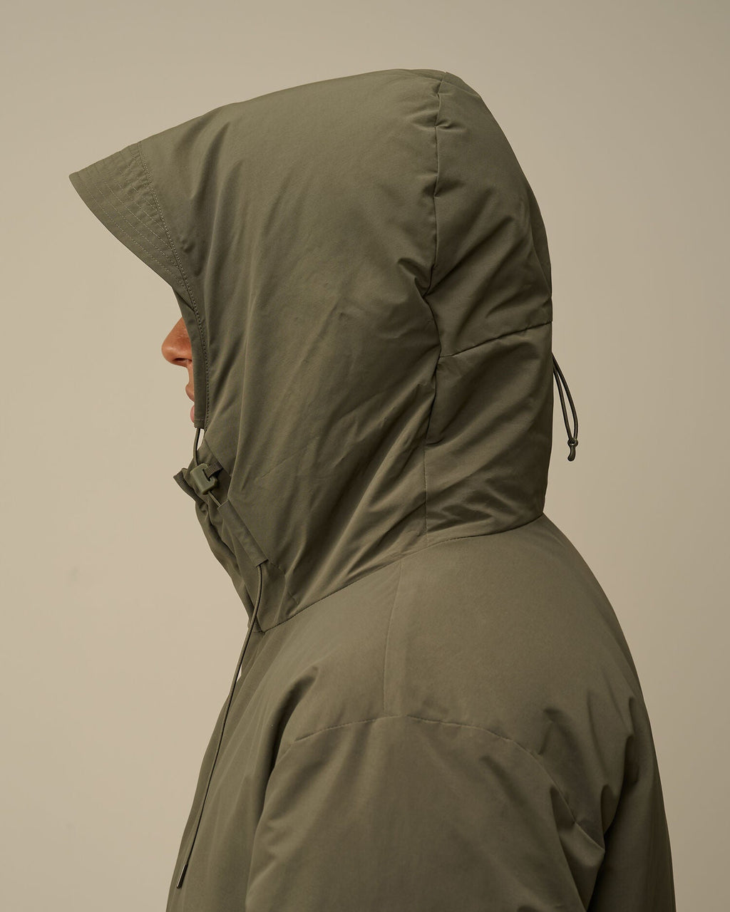 Close-up of the adjustable hood with two-button closure on the CP Company green down parka.
