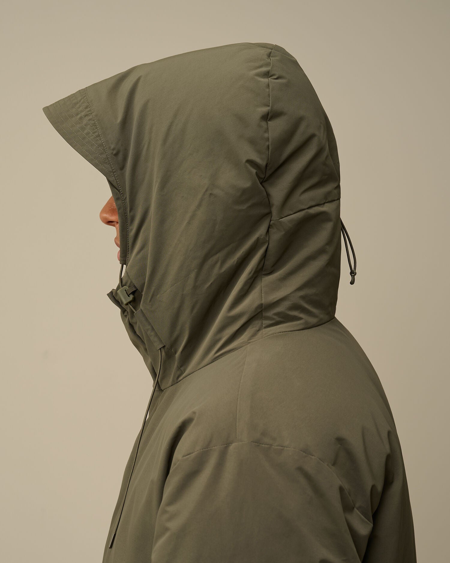 Close-up of the adjustable hood with two-button closure on the CP Company green down parka.
