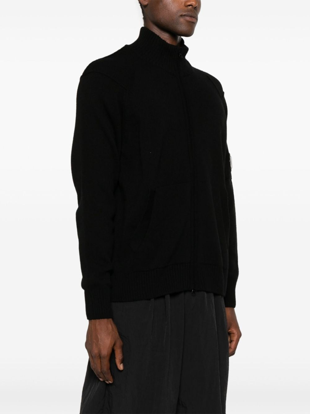 CP Company black labswool lens-detailed zipped cardigan sweater, side view.

