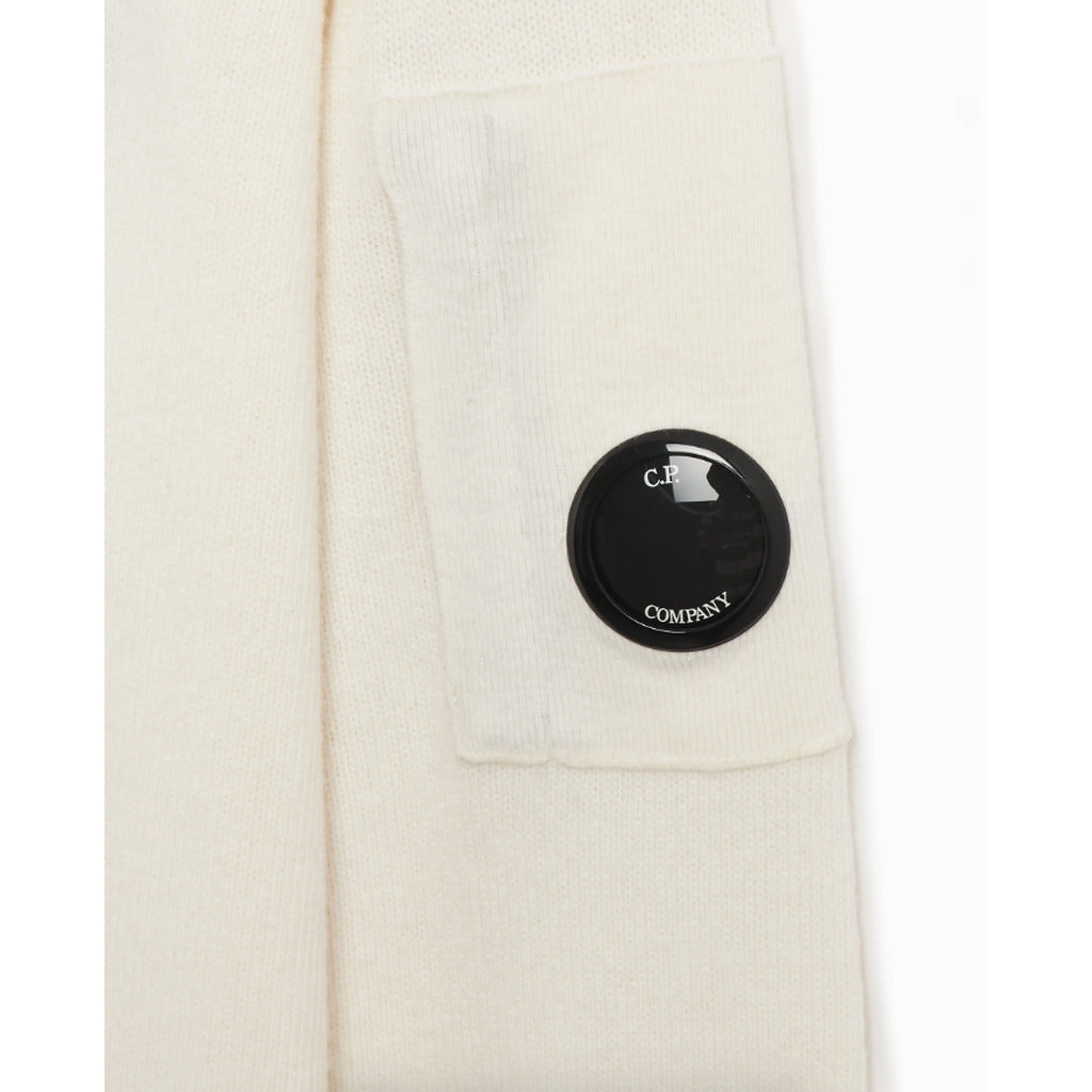 Close-up of the iconic CP Company goggle on the side zip pocket of the white wool blend sweater.
