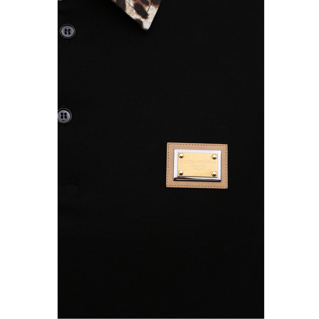 Detail of the leather and metal Dolce & Gabbana logo applied on the chest of the black polo
