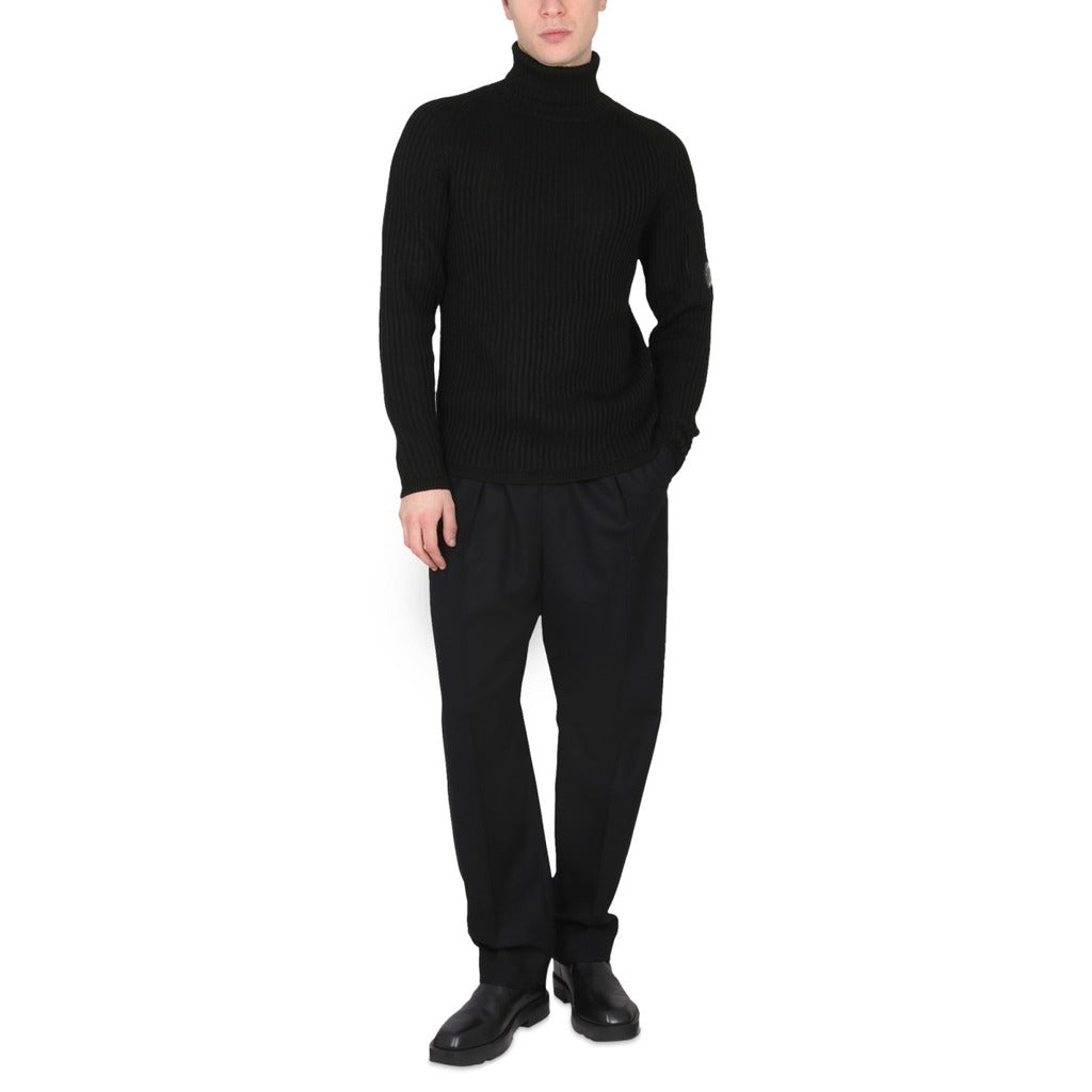 Model showcasing the fit of the CP Company black wool blend goggle pocket turtleneck.
