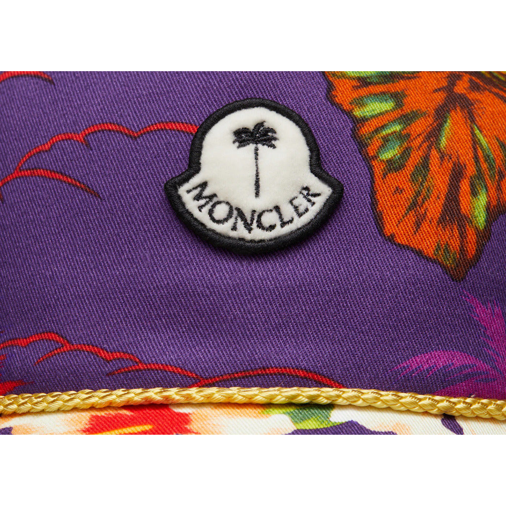 Close-up of the Moncler logo patch on the front of the Palm Angels floral cap

