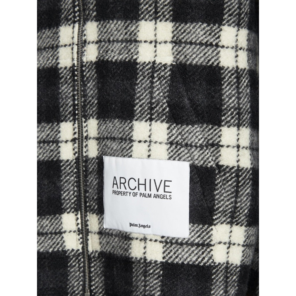 Close-up of the 'Archive Property of Palm Angels' patch on the check jacket

