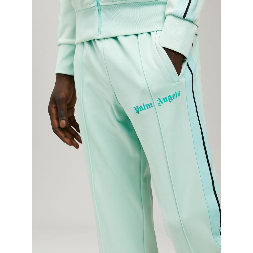 Close-up of the Palm Angels logo printed on the neon green track pants
