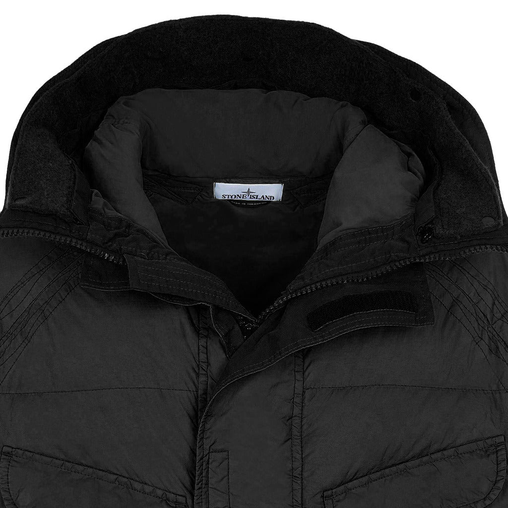 Buttoned front pocket detail on the Stone Island garment-dyed black long coat.

