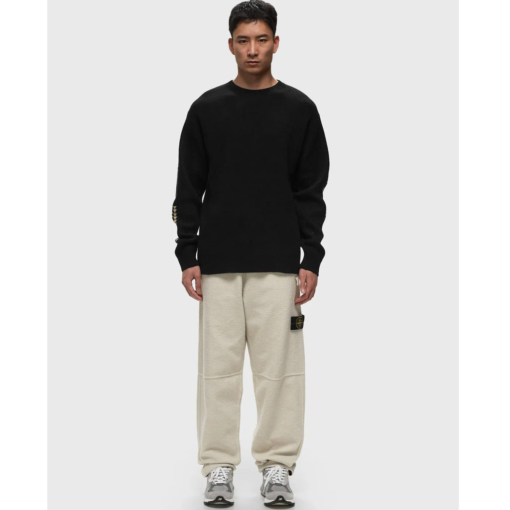 Close-up of the Stone Island badge on the left side of the white fleece sweatpants.
