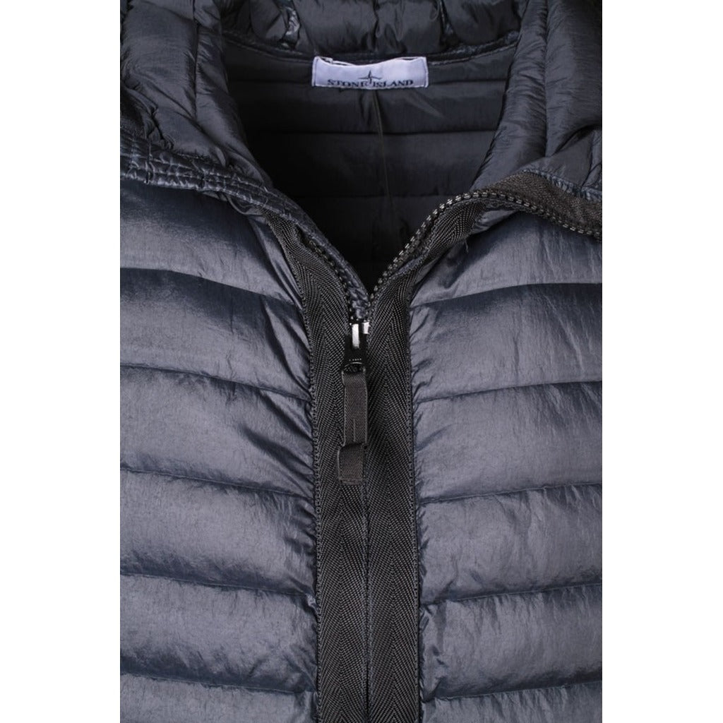 Close-up of the Stone Island logo patch on the sleeve of the blue down jacket.
