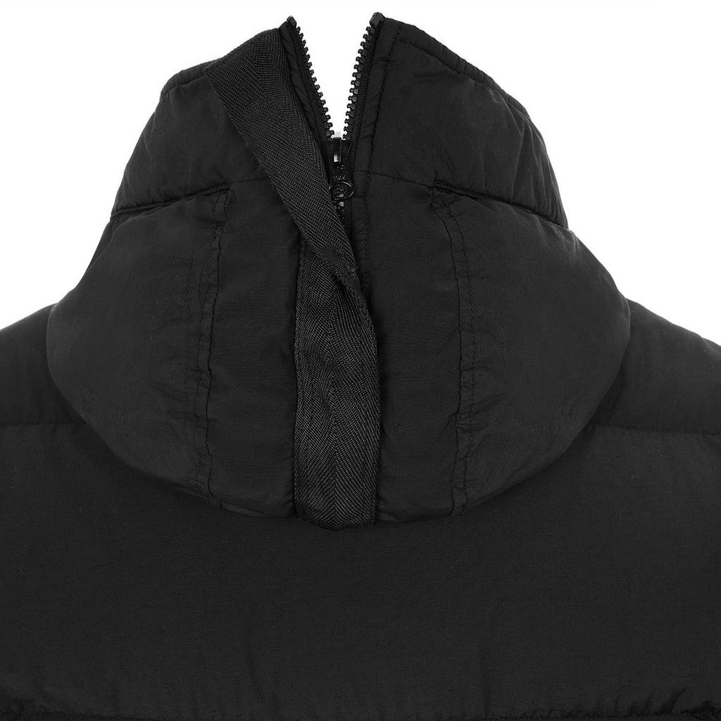 Close-up of the Stone Island logo patch on the sleeve of the black down jacket.
