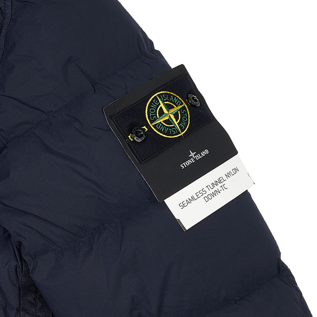 Close-up of the Stone Island logo patch on the sleeve of the blue seamless Down-TC jacket.
