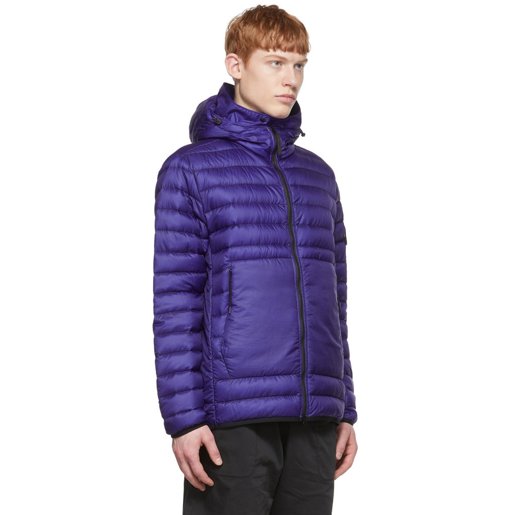 Close-up of the Stone Island logo patch on the sleeve of the purple/blue down jacket.
