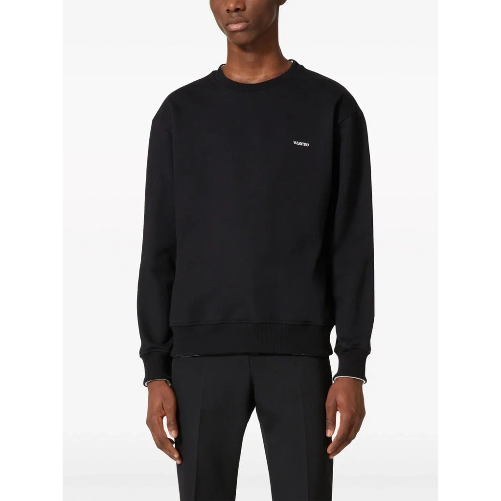 Valentino Garavani black cotton crewneck sweatshirt with contrasting logo print on chest, front view.

